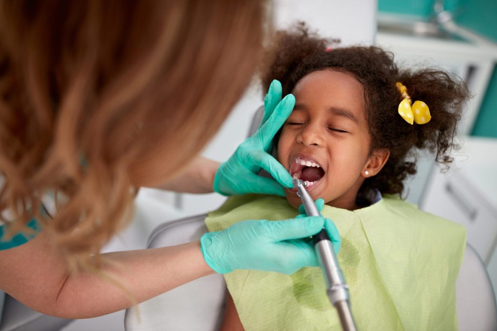 Happy child at pediatric dentist in Toronto during a gentle dental procedure.